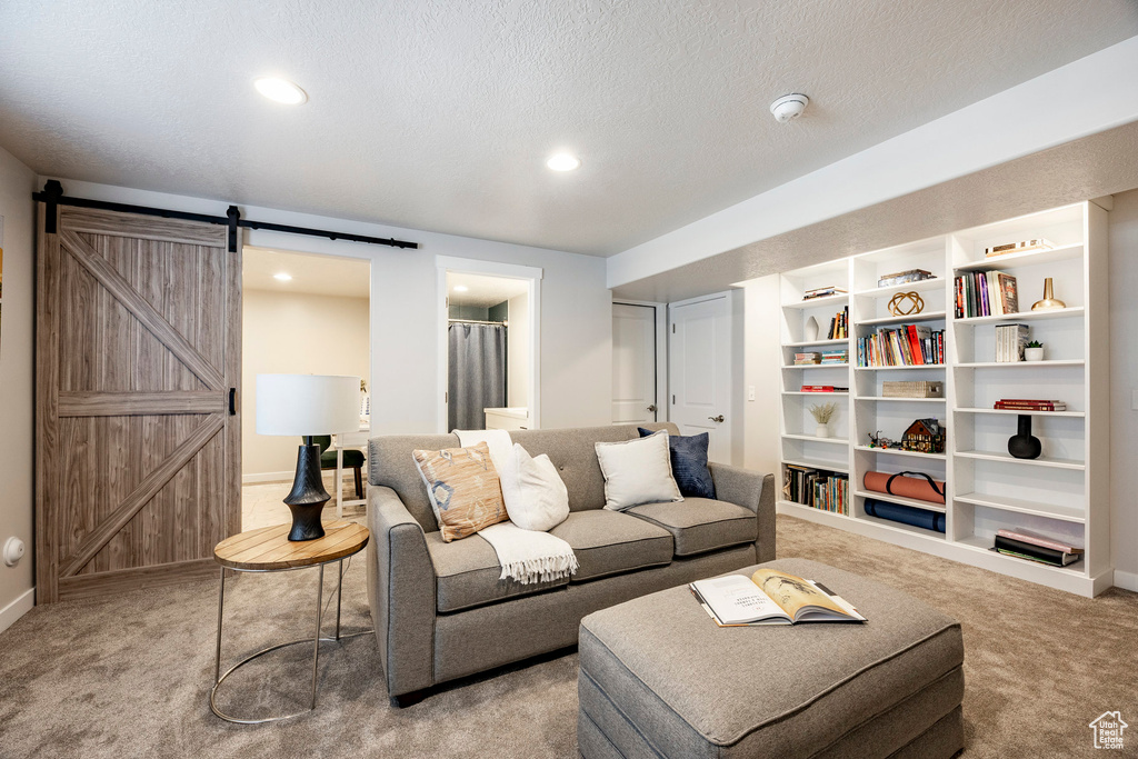 Living area featuring carpet, a barn door, a textured ceiling, and recessed lighting