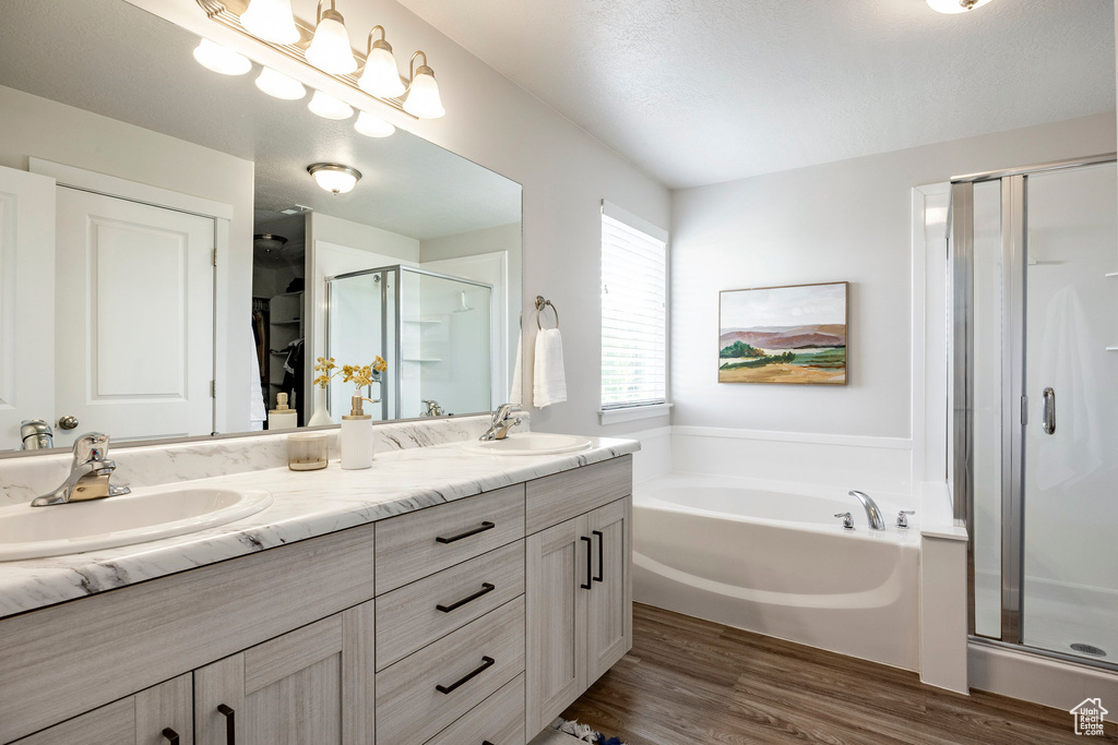 Full bathroom featuring a shower stall, double vanity, a garden tub, and wood finished floors