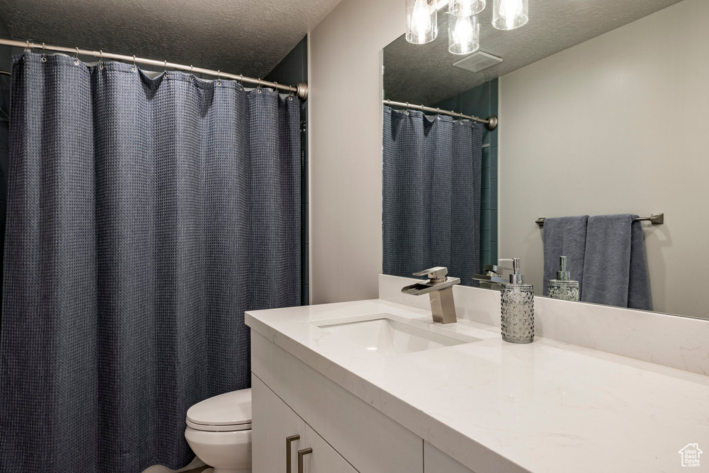Bathroom with a textured ceiling, vanity, and a shower with shower curtain