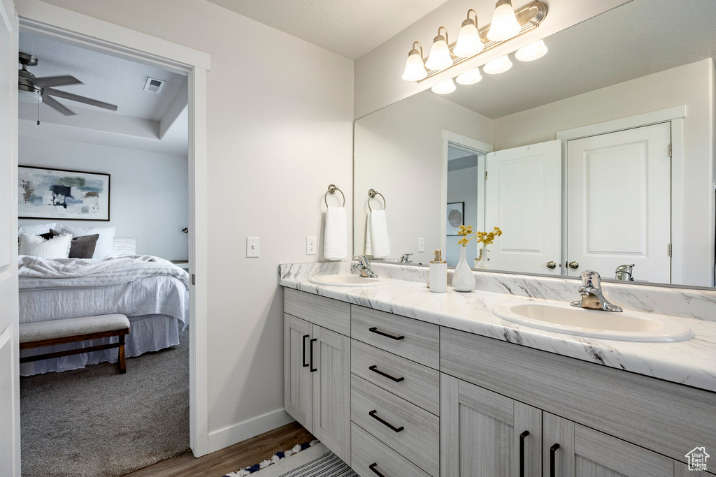 Ensuite bathroom with double vanity, wood finished floors, and ceiling fan