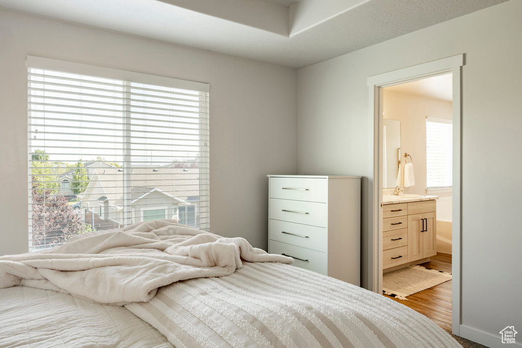 Bedroom with ensuite bathroom and wood finished floors