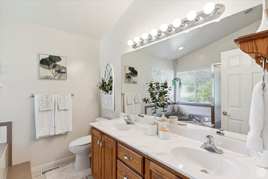 Full bathroom featuring lofted ceiling, a bath, double vanity, a shower stall, and tile patterned flooring