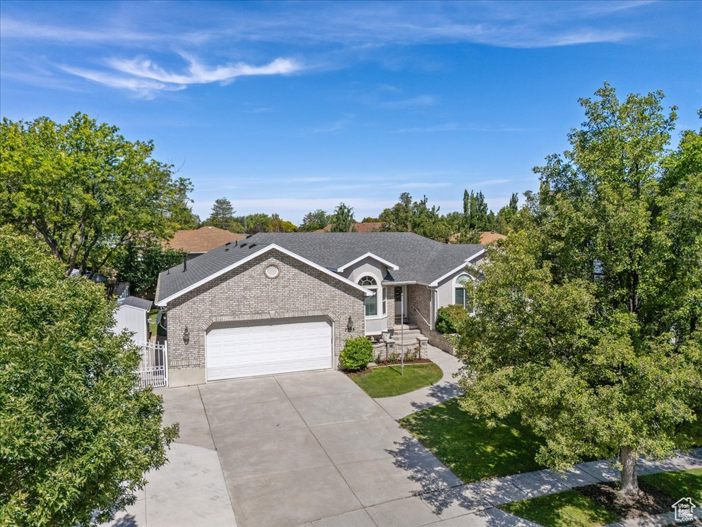 View of front of house featuring brick siding, an attached garage, driveway, and a gate