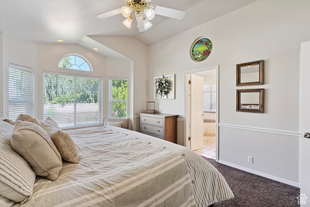 Bedroom featuring carpet flooring, lofted ceiling, ensuite bathroom, and a ceiling fan