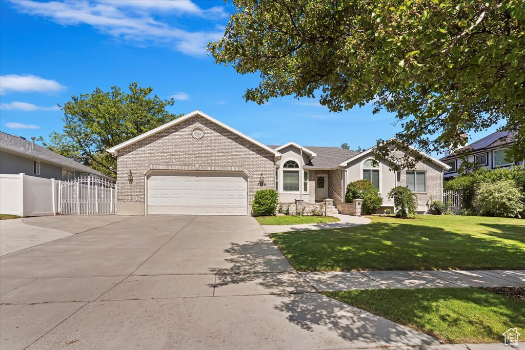 Ranch-style home featuring brick siding, a garage, concrete driveway, and a gate