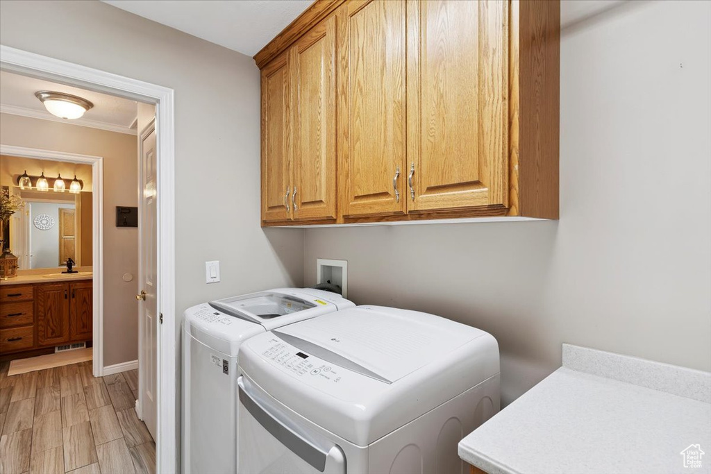 Laundry room featuring cabinet space, separate washer and dryer, and crown molding
