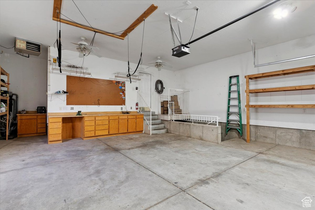 Garage with a workshop area, a heating unit, and a garage door opener