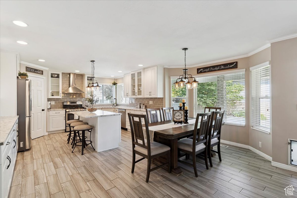 Dining room featuring a chandelier, light wood finished floors, crown molding, and recessed lighting