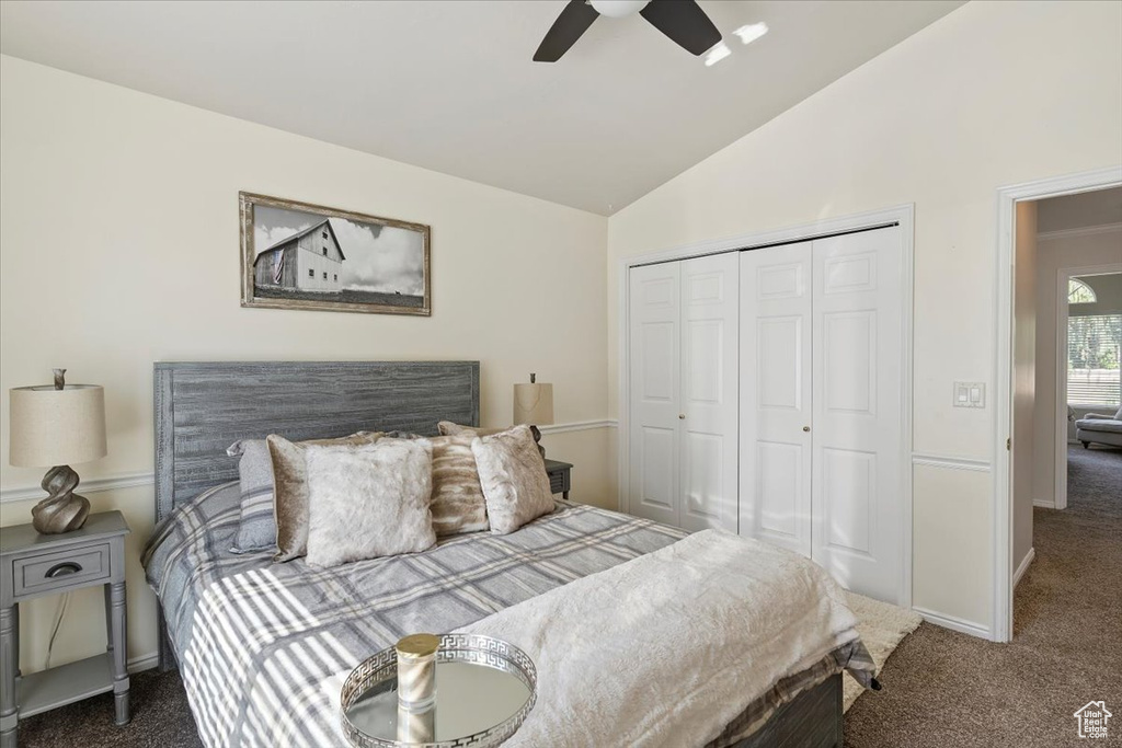 Bedroom featuring dark colored carpet, vaulted ceiling, a closet, and a ceiling fan