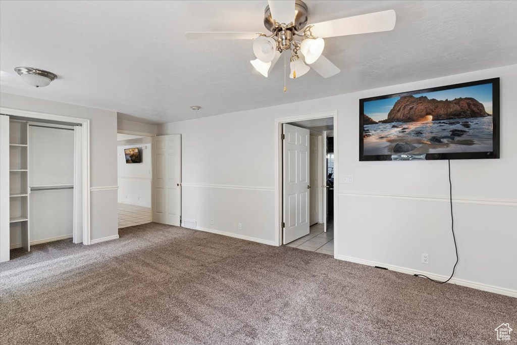Unfurnished bedroom with carpet floors, a ceiling fan, and a closet