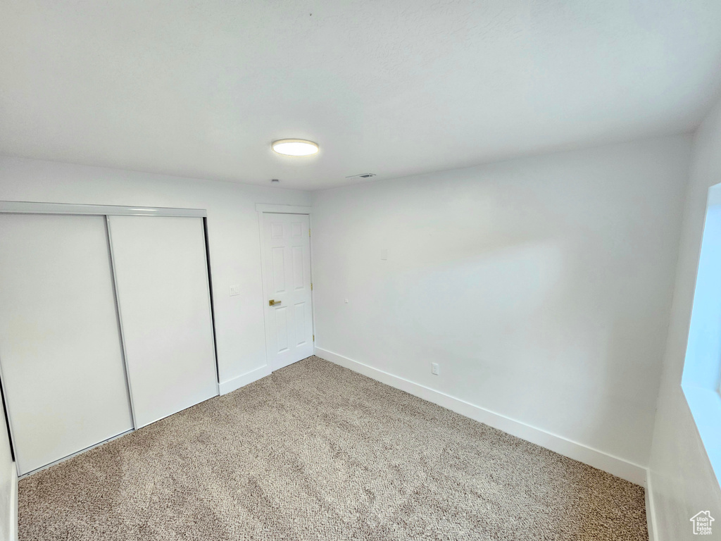 Unfurnished bedroom with carpet and a closet