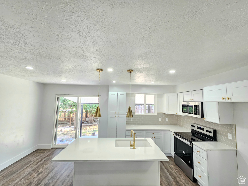 Kitchen featuring stainless steel appliances, dark wood-style flooring, backsplash, light countertops, and a textured ceiling