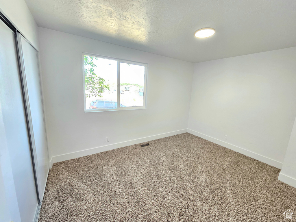 Unfurnished bedroom with carpet floors, a closet, and a textured ceiling
