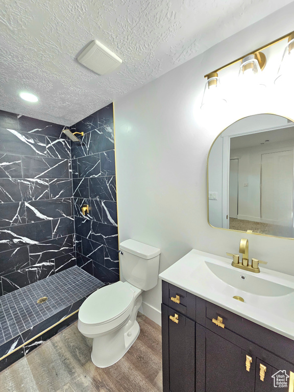 Full bath with wood finished floors, vanity, a shower stall, and a textured ceiling