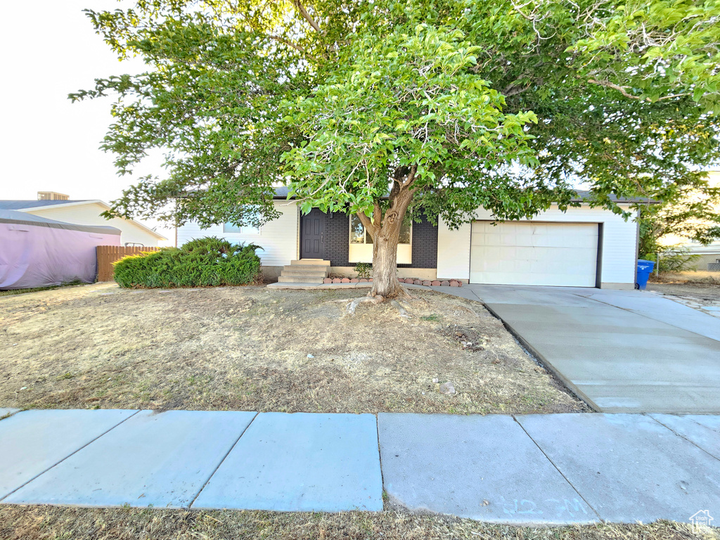 Obstructed view of property with an attached garage, driveway, and brick siding