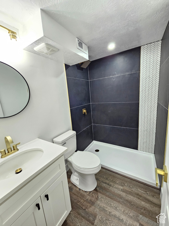 Bathroom featuring a stall shower, wood finished floors, vanity, and a textured ceiling