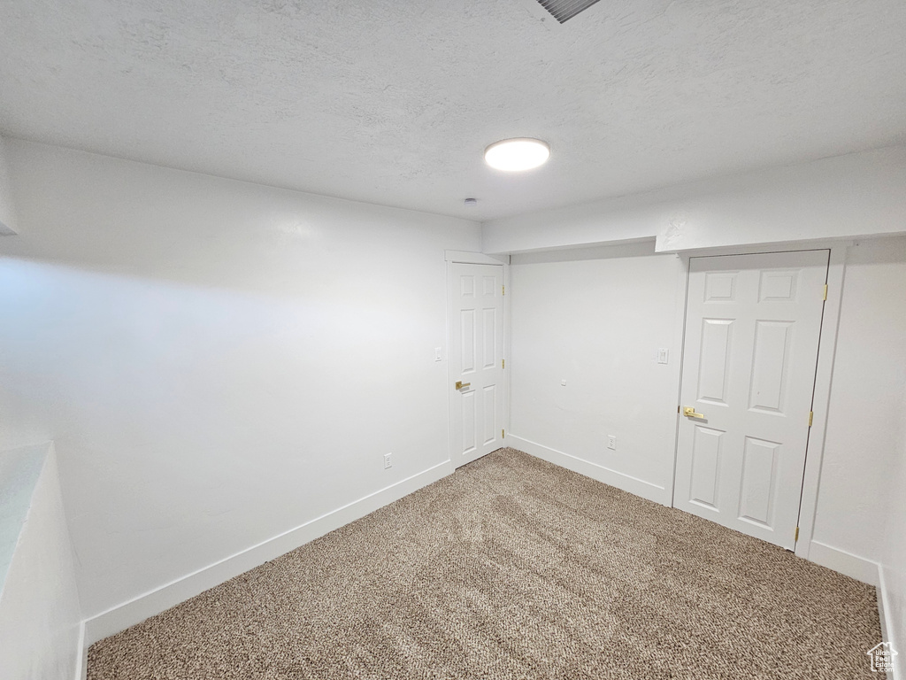 Finished below grade area with carpet flooring and a textured ceiling