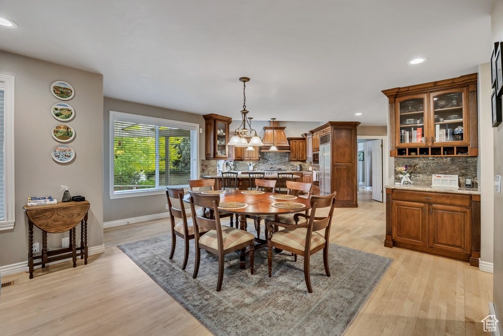 Dining area with light wood finished floors, recessed lighting, and a chandelier