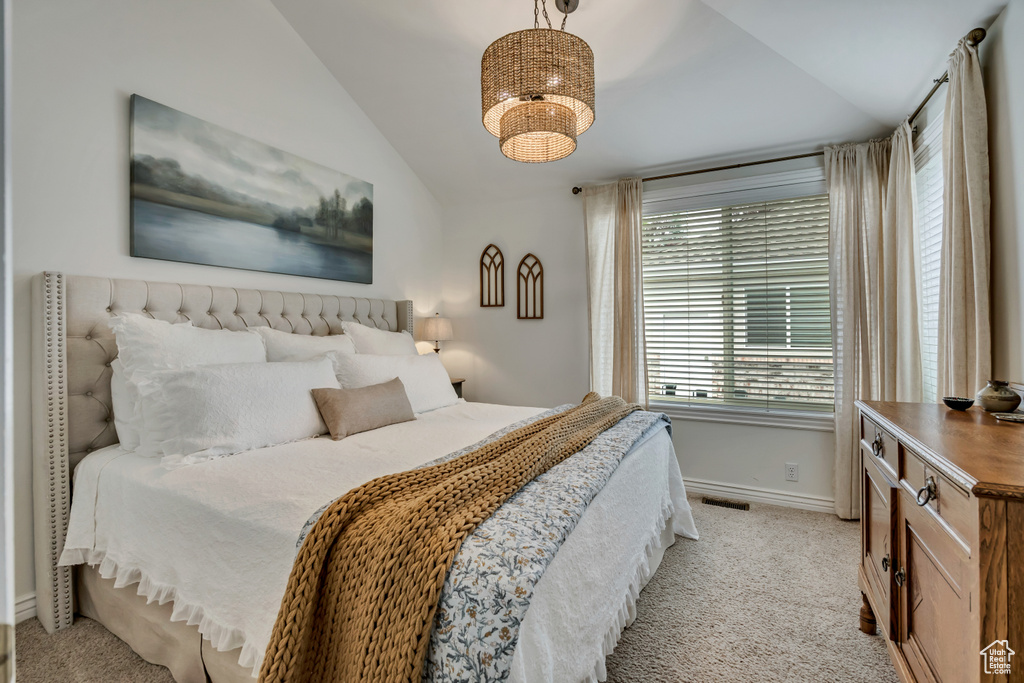 Bedroom featuring vaulted ceiling, light colored carpet, and a chandelier