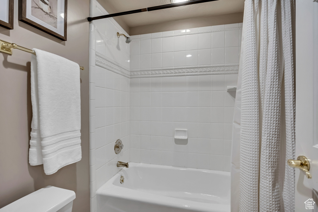 Full bath featuring shower / bath combo with shower curtain and toilet
