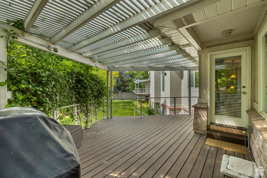Wooden terrace featuring a grill and a pergola