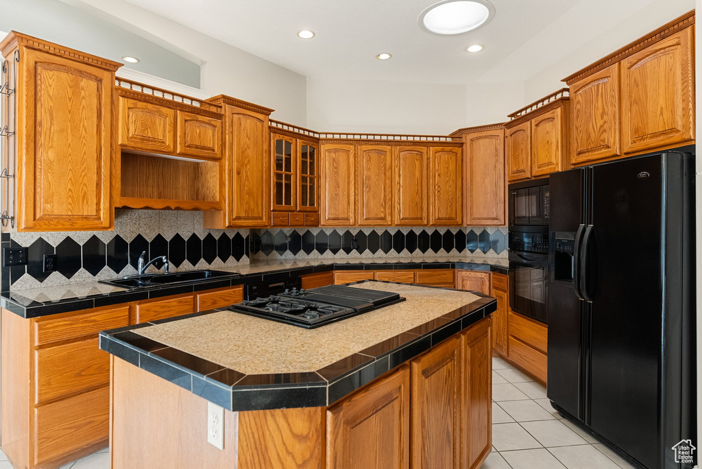 Kitchen featuring black appliances, a kitchen island, brown cabinetry, light tile patterned flooring, and recessed lighting