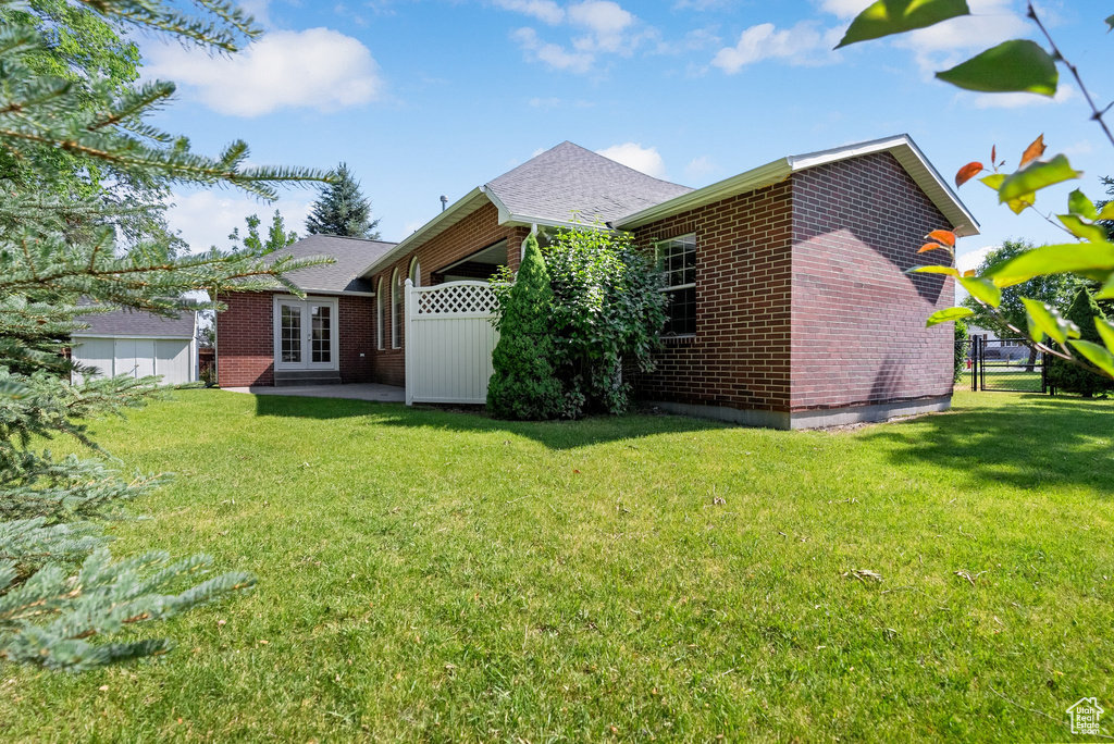 Rear view of house featuring french doors, brick siding, and roof with shingles
