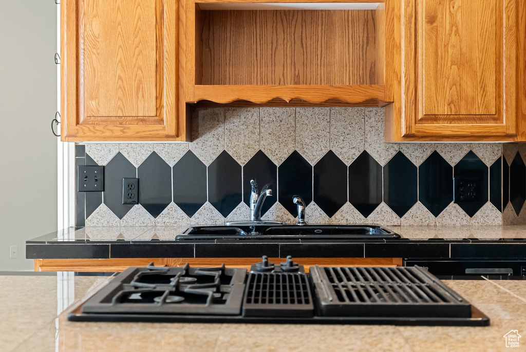 Kitchen view of stovetop with downdraft, backsplash, and light countertops