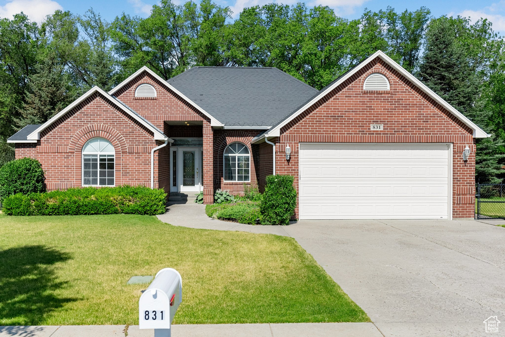 View of front of property featuring brick siding, an attached garage, a front yard, and concrete driveway