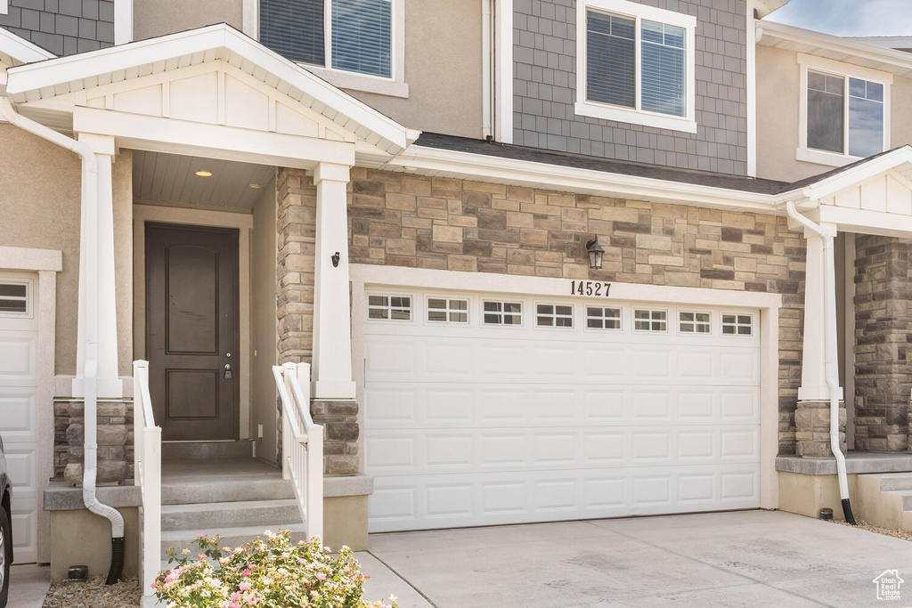 Property entrance featuring a garage, stone siding, and driveway