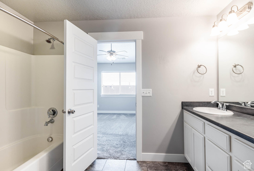 Full bathroom with vanity, a ceiling fan, shower / bath combination, a textured ceiling, and tile patterned floors