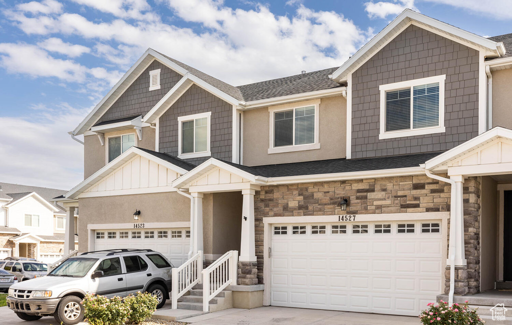 View of front of home featuring stone siding, a garage, concrete driveway, board and batten siding, and roof with shingles