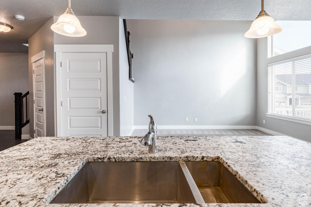 Kitchen featuring light stone counters, decorative light fixtures, healthy amount of natural light, and a textured ceiling
