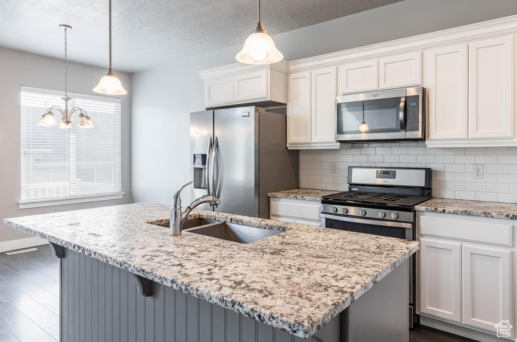 Kitchen featuring stainless steel appliances, white cabinetry, dark wood finished floors, a chandelier, and a textured ceiling