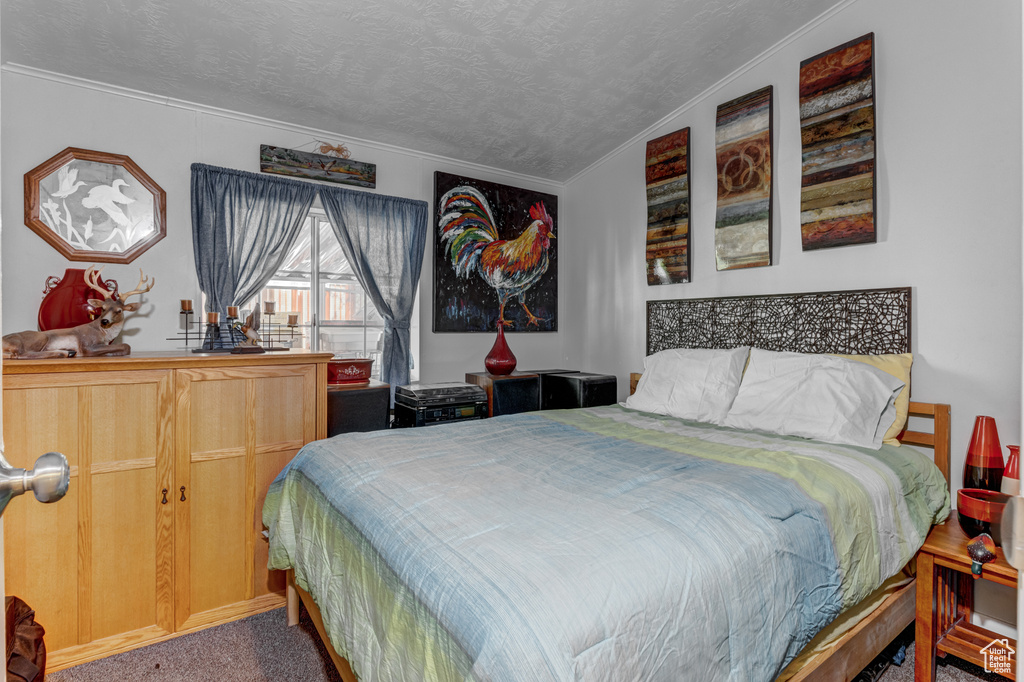 Bedroom with ornamental molding, carpet, and a textured ceiling