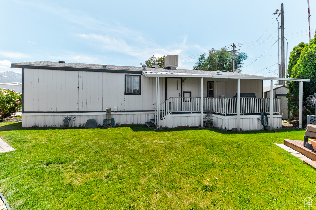 Back of property featuring covered porch and a lawn