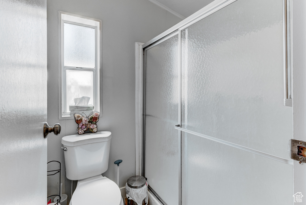 Bathroom featuring a shower with shower door and toilet