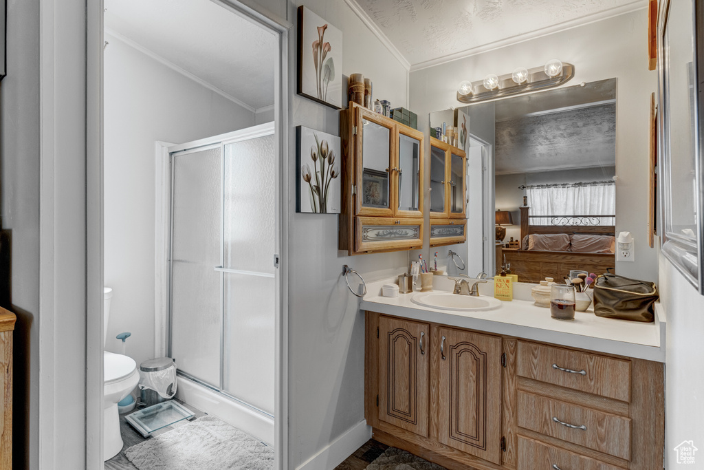 Ensuite bathroom featuring crown molding, a stall shower, and vanity