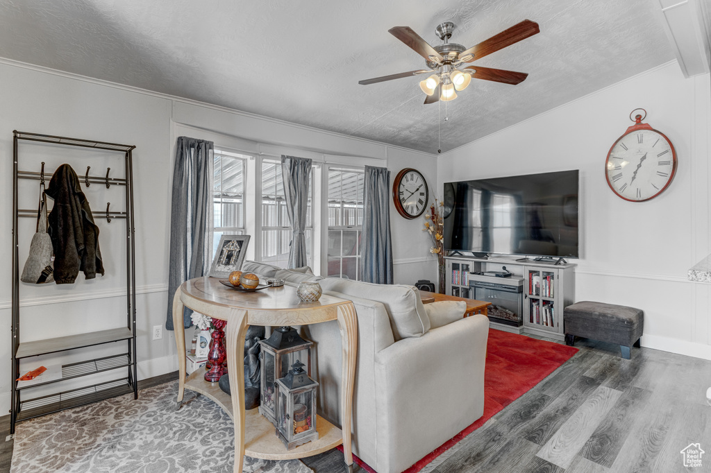 Living room featuring wood finished floors, ceiling fan, a textured ceiling, and crown molding