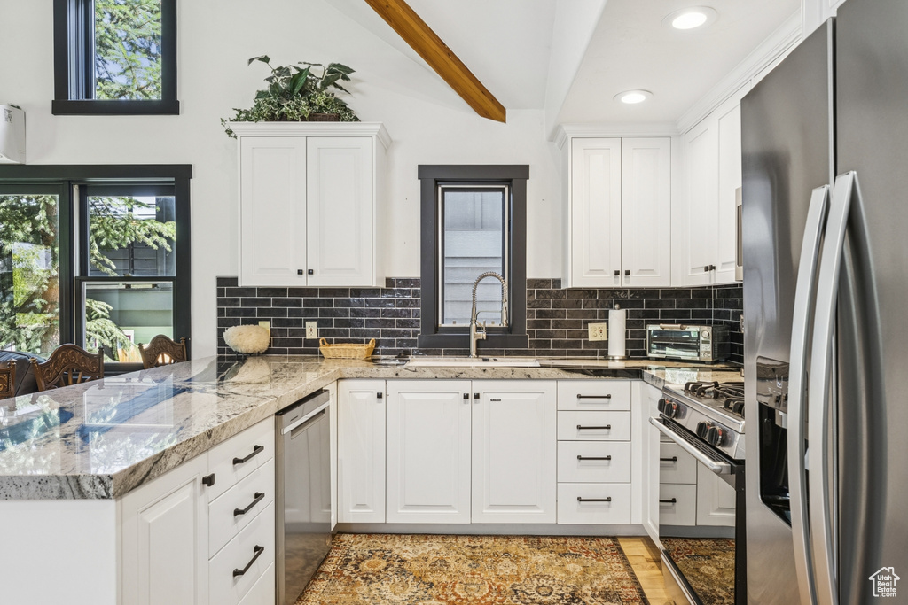 Kitchen featuring stainless steel appliances, recessed lighting, white cabinets, tasteful backsplash, and a peninsula
