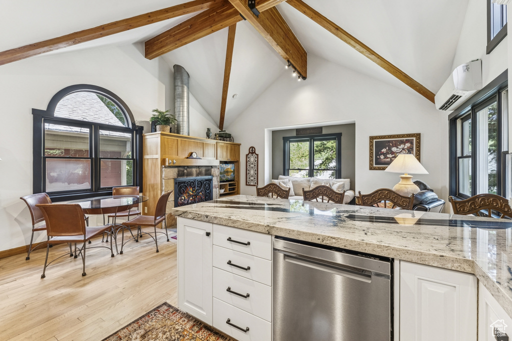 Kitchen with dishwasher, beam ceiling, light wood-type flooring, a wall mounted air conditioner, and a stone fireplace
