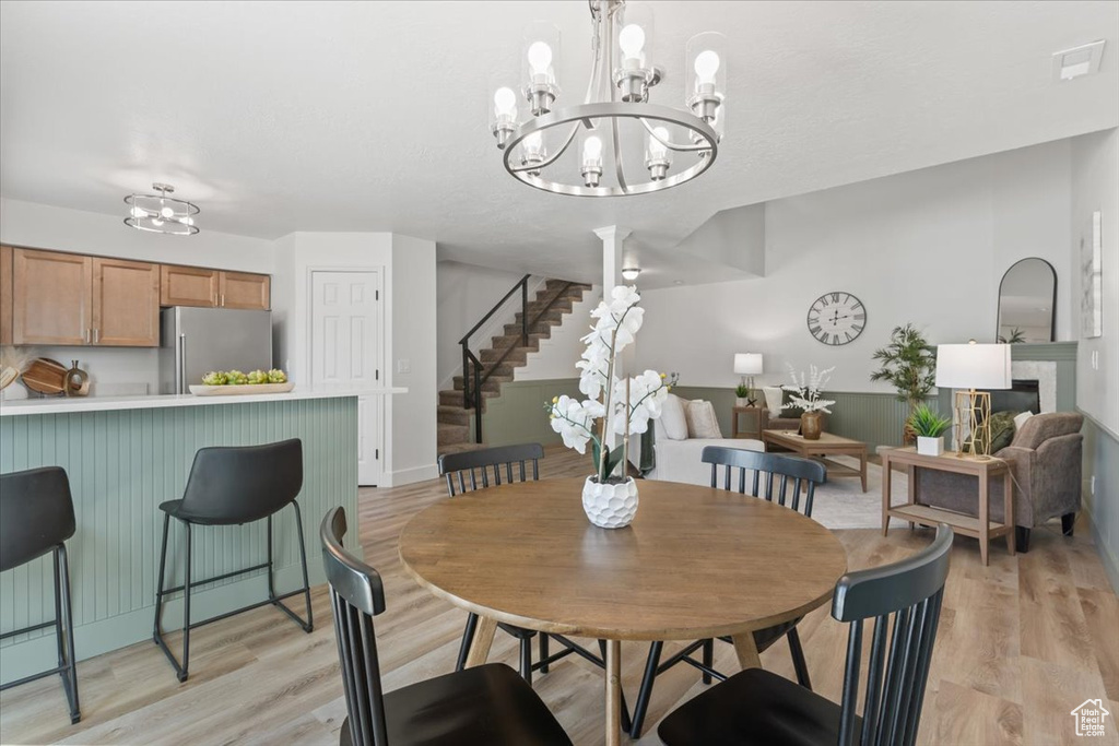Dining room with a chandelier, light wood-style floors, and stairway
