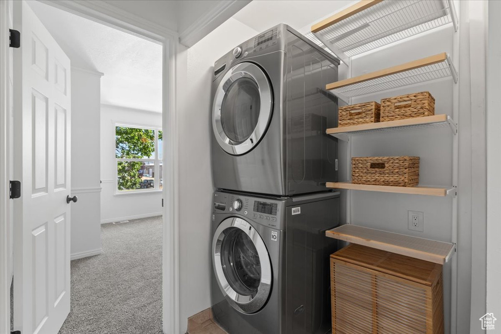 Laundry room featuring stacked washer / drying machine and carpet flooring