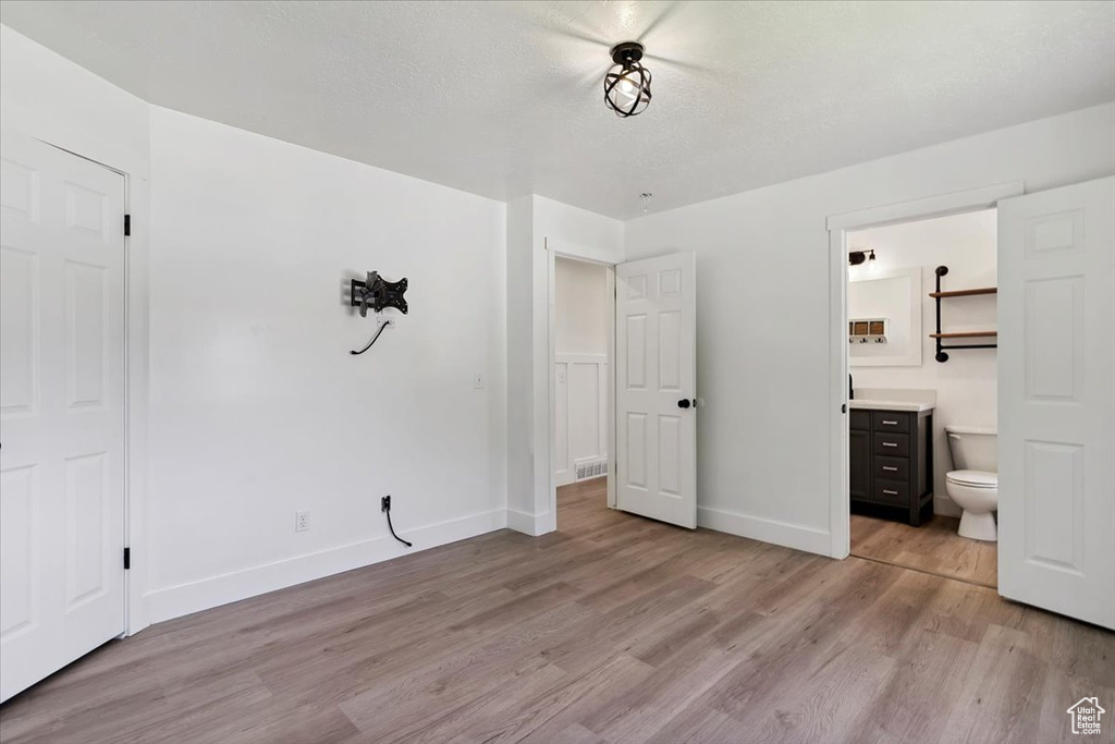 Unfurnished bedroom featuring light wood-type flooring and ensuite bathroom