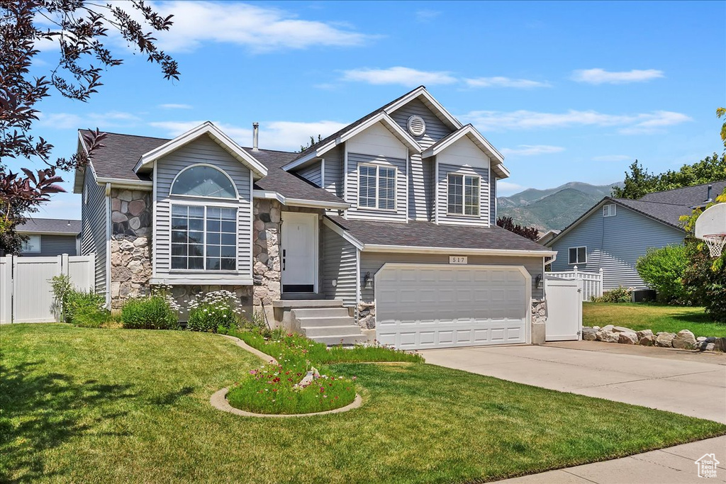 View of front of property featuring stone siding, driveway, an attached garage, and a shingled roof