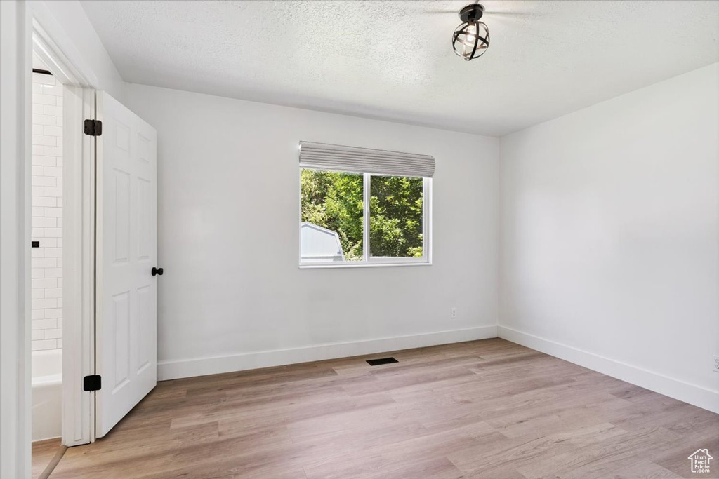 Unfurnished room featuring light wood-type flooring and a textured ceiling