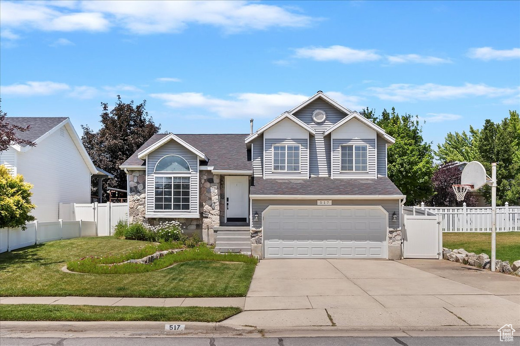 Tri-level home featuring stone siding, concrete driveway, an attached garage, and a shingled roof