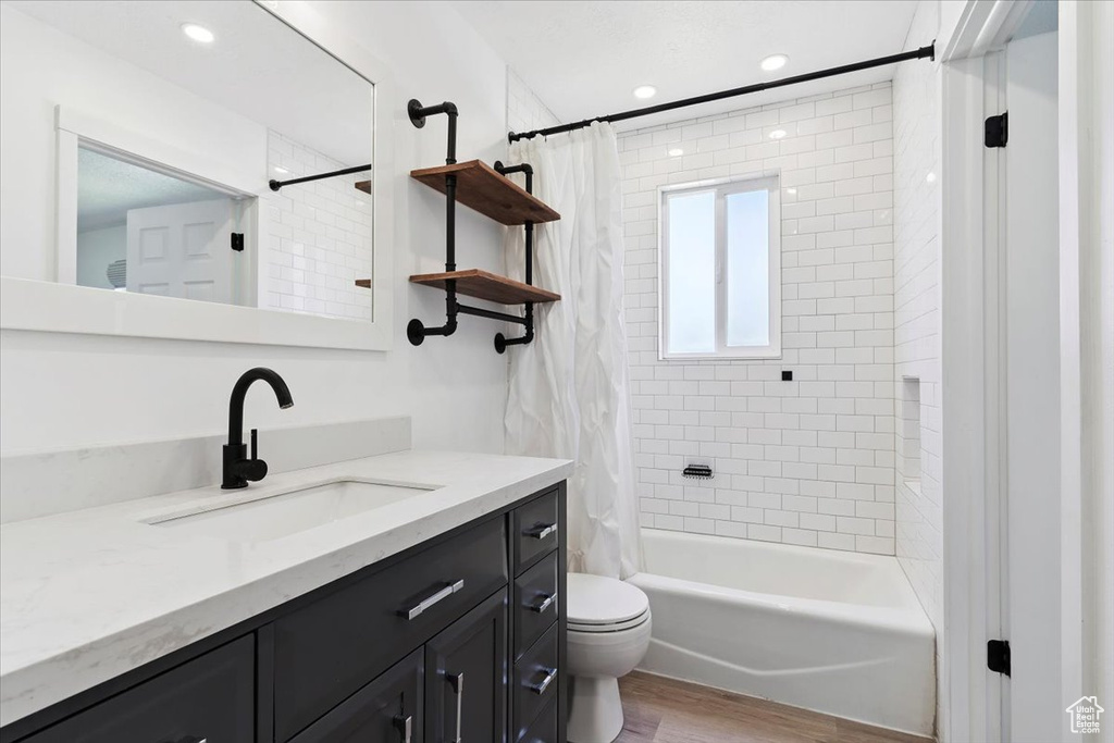 Full bathroom with vanity, wood finished floors, shower / tub combo, and recessed lighting