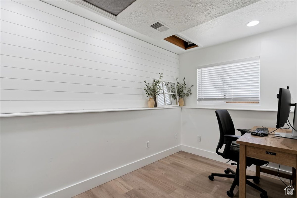 Office area featuring light wood-style floors and a textured ceiling