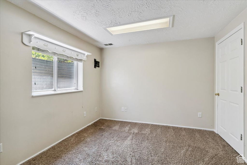 Carpeted spare room featuring a textured ceiling and baseboards